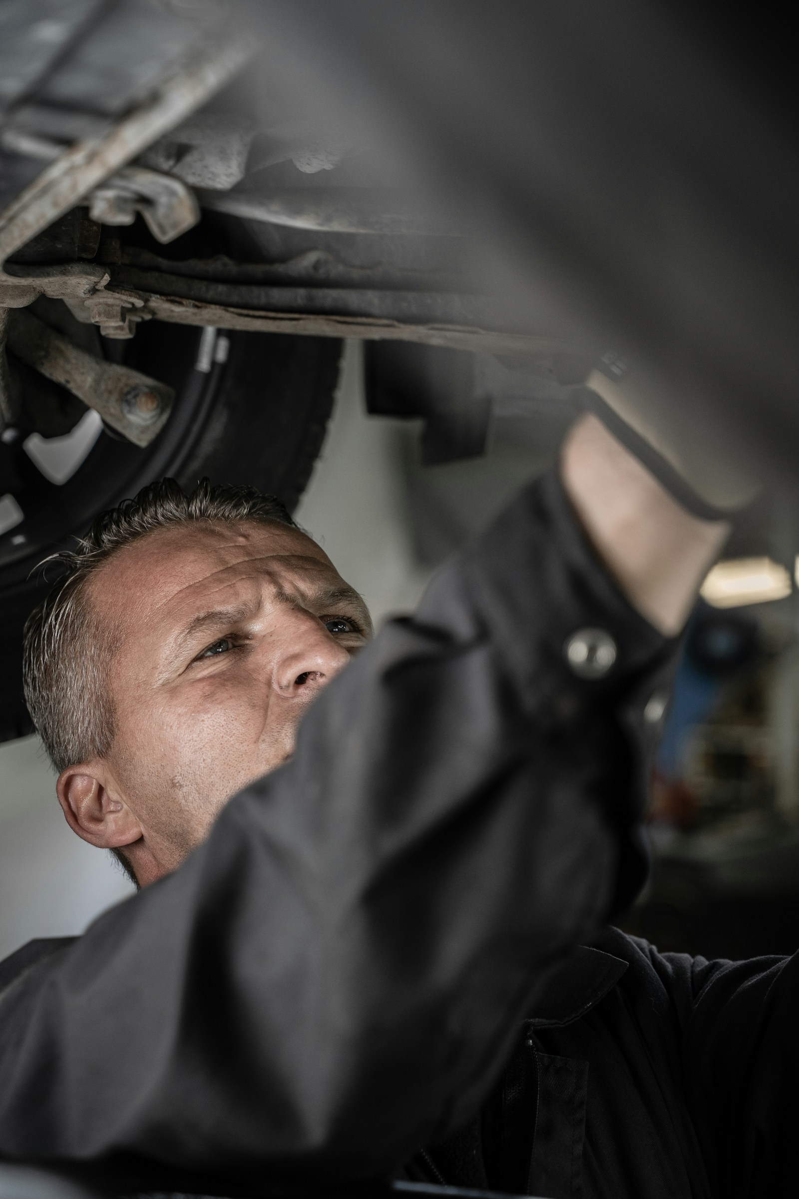 Mechanik kontroluje podvozek a nápravu auta na zvedáku